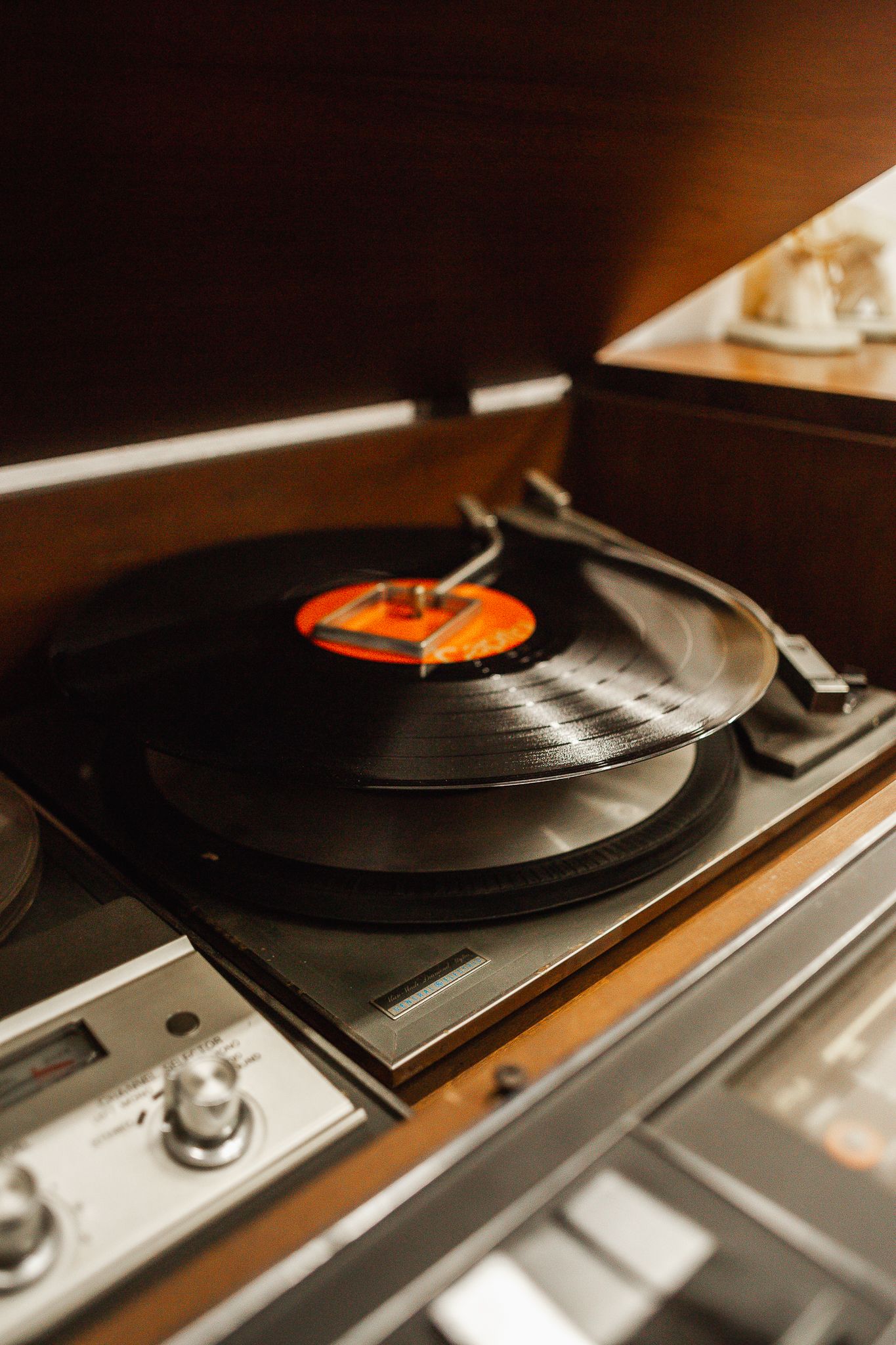 Vintage turntable playing a record inside a wood console